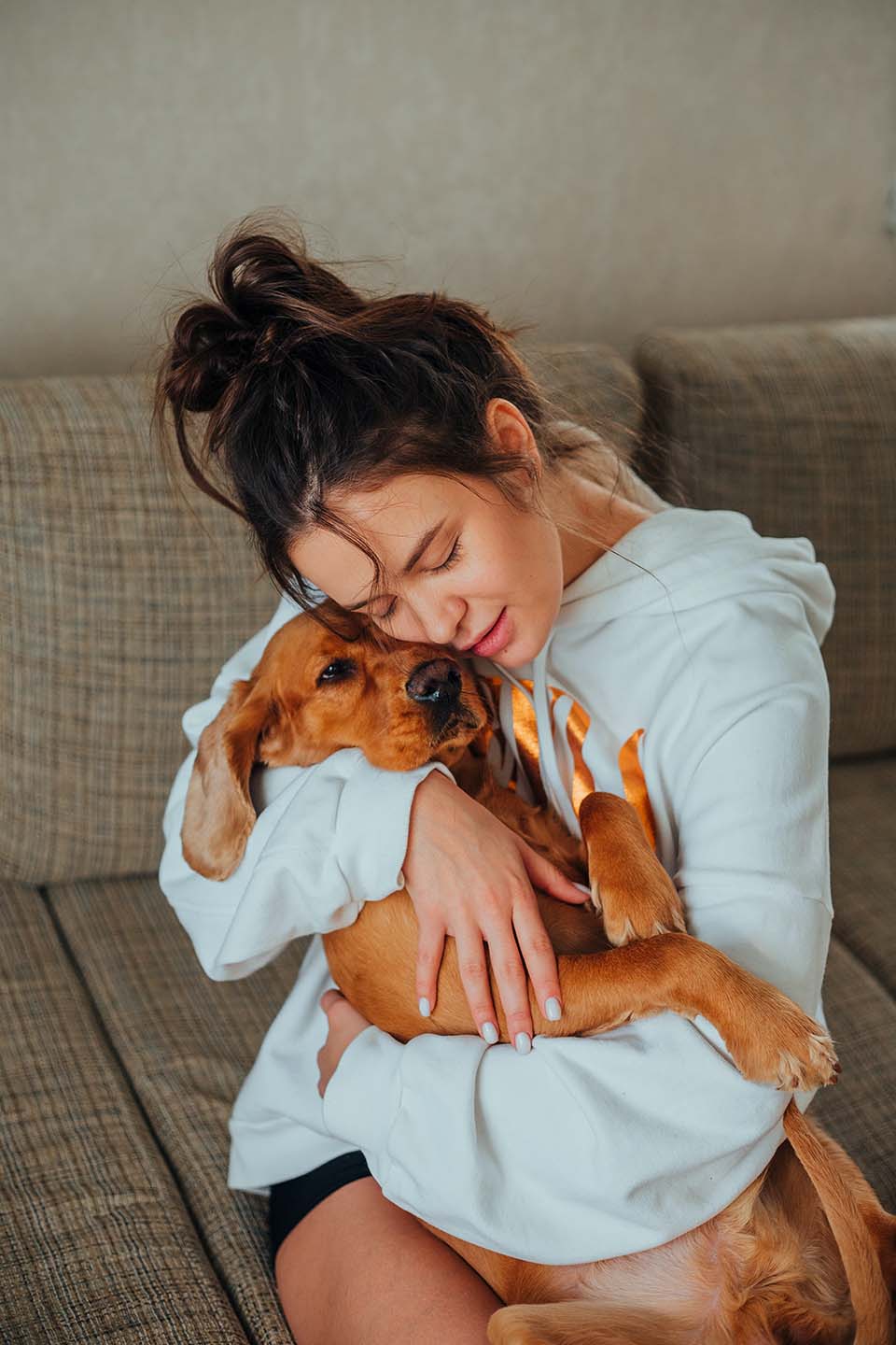 woman hugging dog sitting on couch